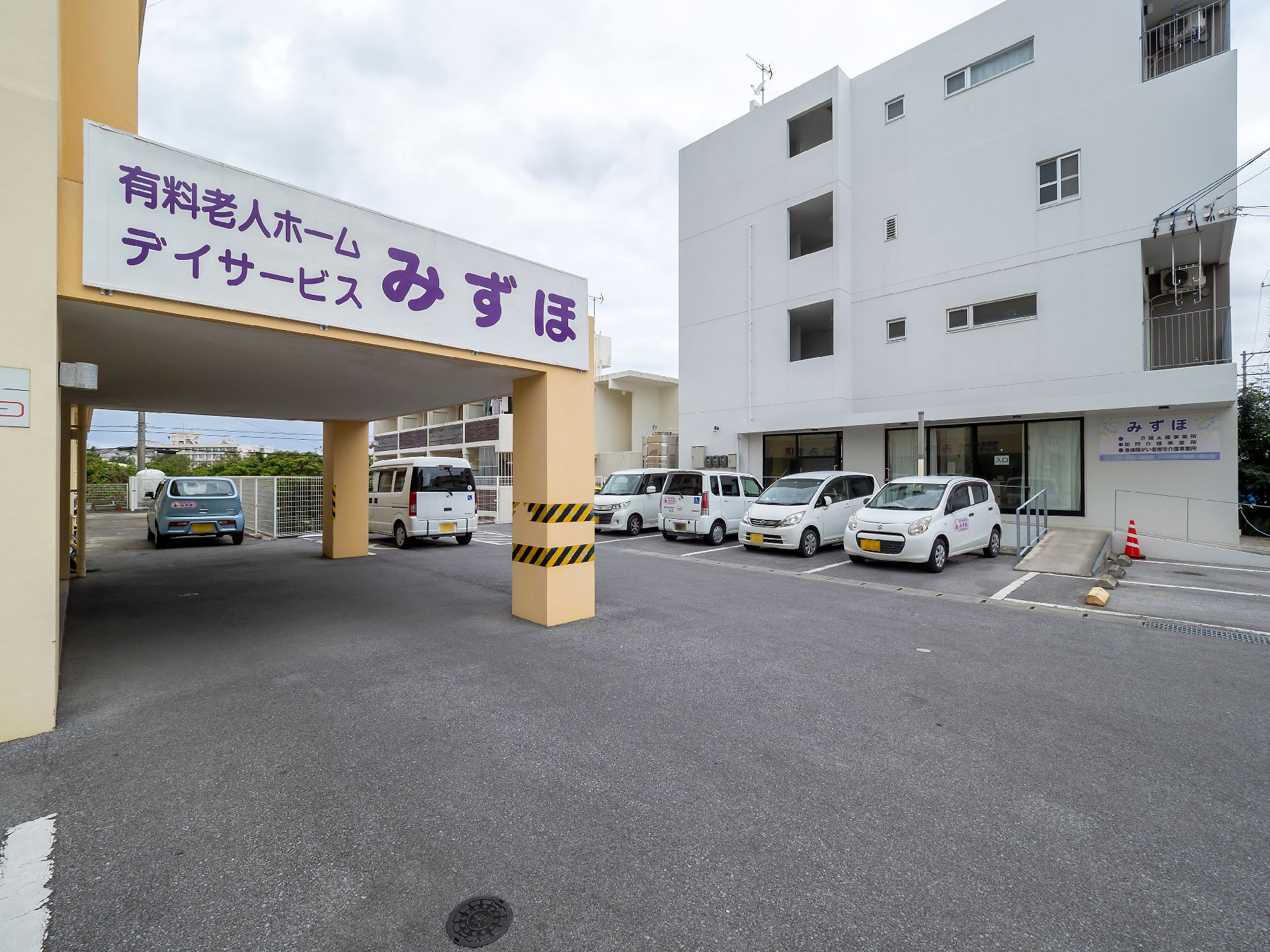 ホーム名と併設事業所名が書かれている外壁は山吹色で、屋外階段が付いている。