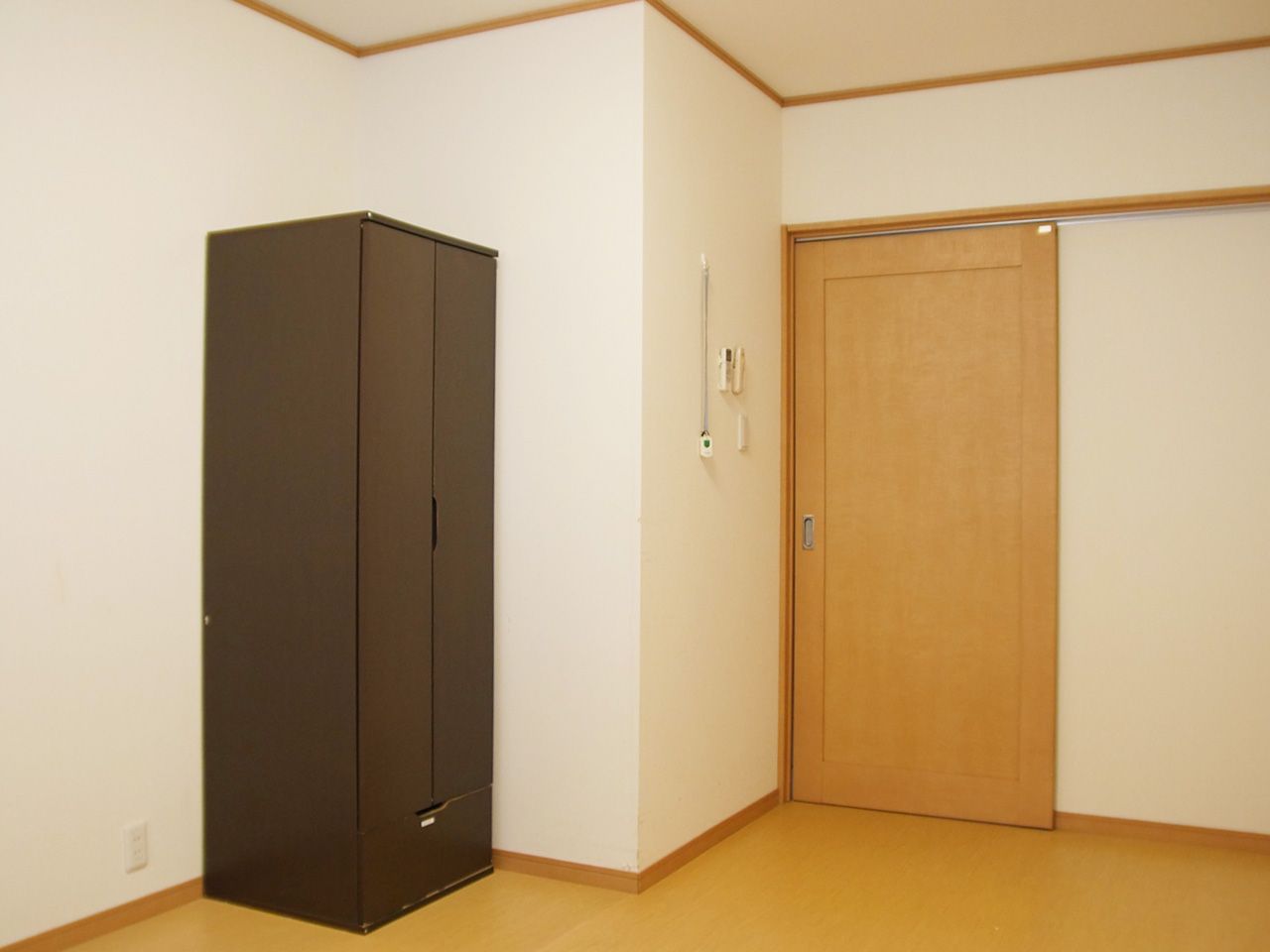 白い外壁の2階建ての建物には緑の三角屋根が付き、周辺には自然が多い。