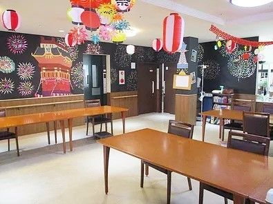 木製のダイニングテーブルが置かれ、ぬくもりが感じられる館内。夏祭り用の飾りが設置されている。