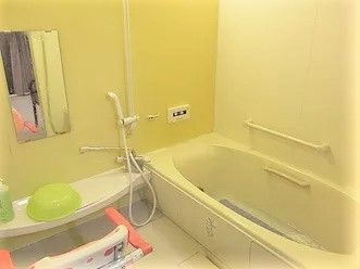白を基調とした浴室には一人用の浴槽とシャワーや手すり、シャワーチェアが設置されている。
