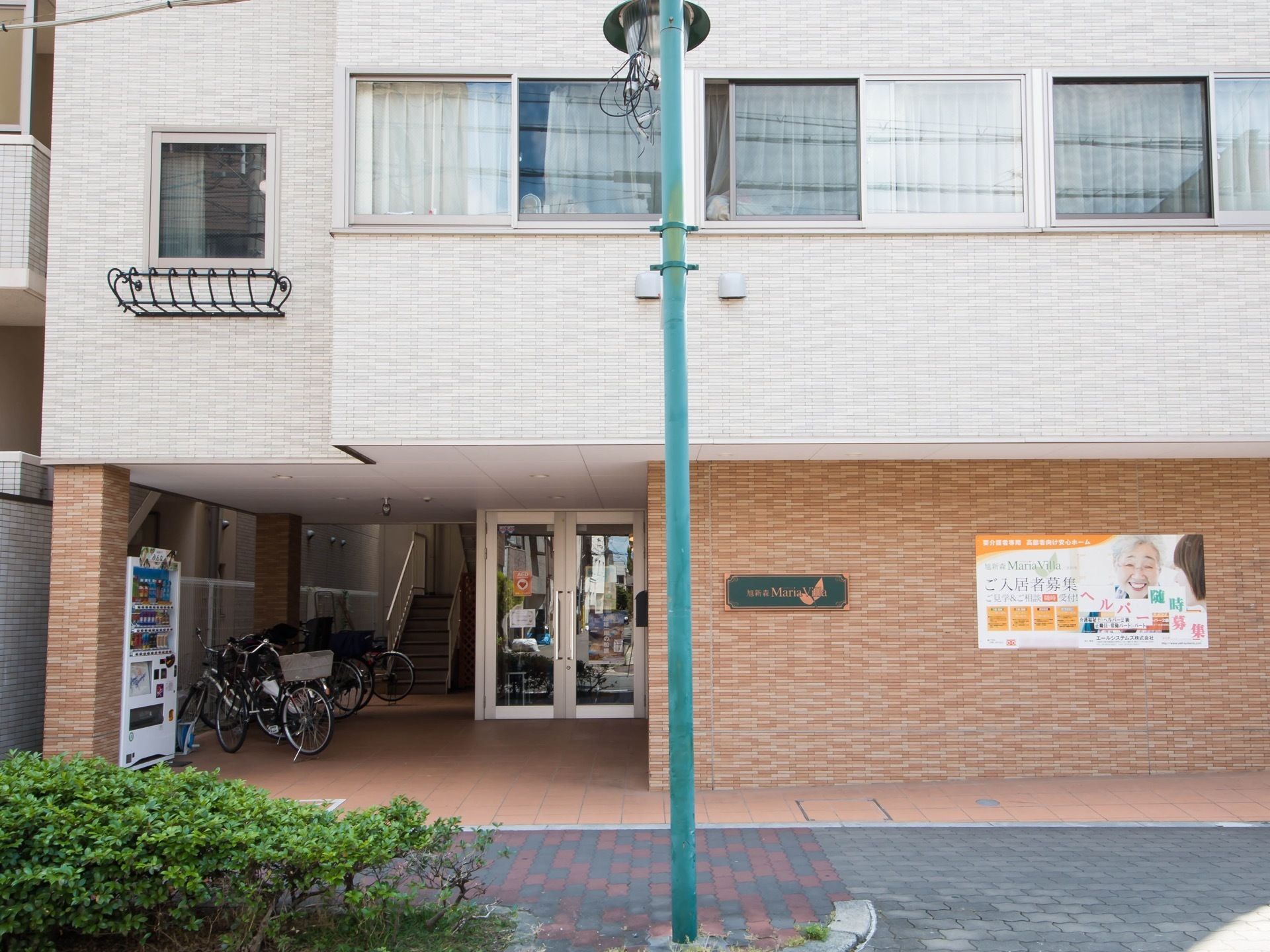 道路から見た施設一階部分。二階から上とは外壁の色が違っている。階段は玄関を通らずピロティから直接出入りする。
