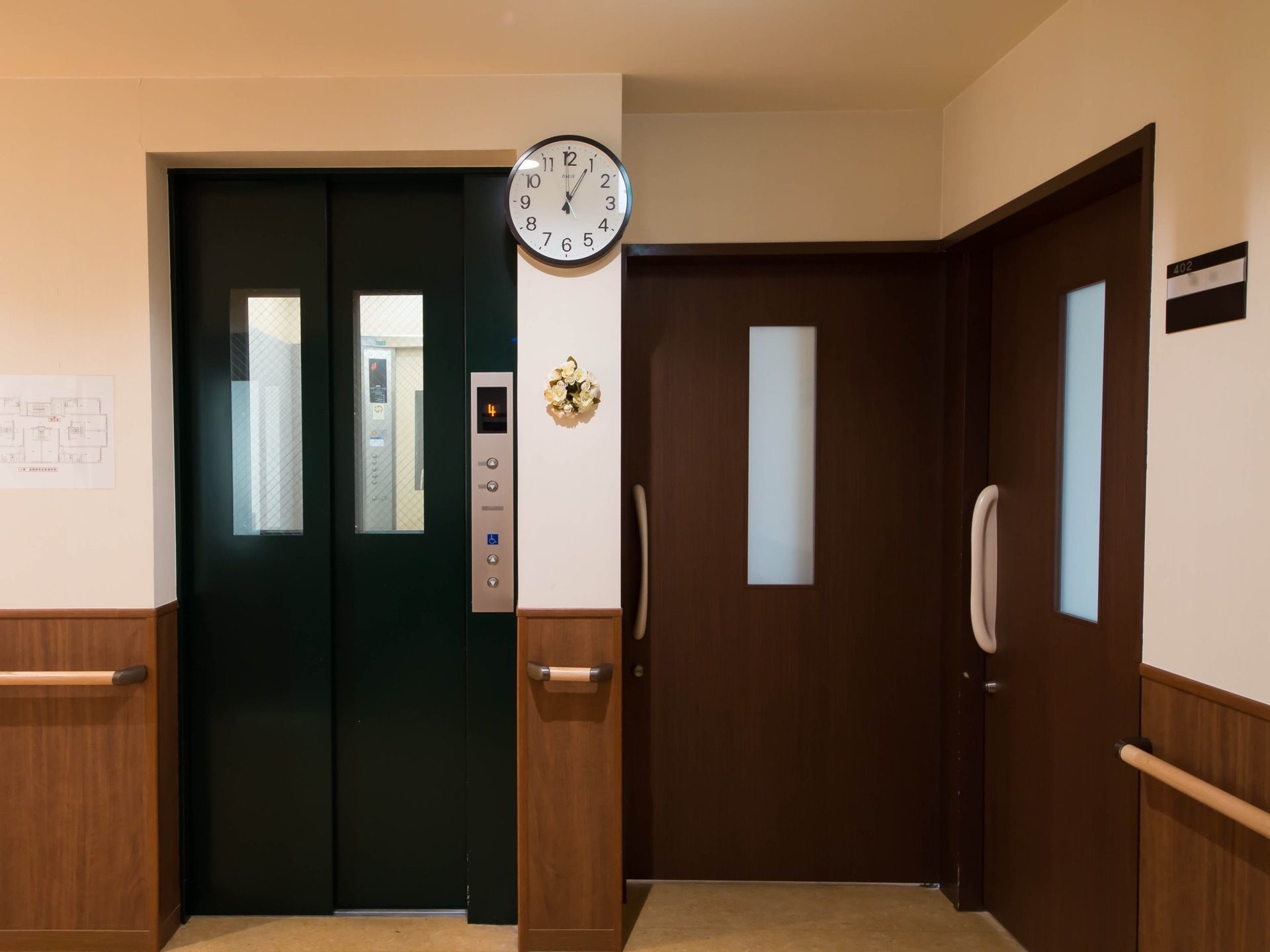 １階から５階までを結ぶエレベーター。ドアはダークな色合いのモスグリーンで、ガラスを通して中が見えるタイプになっている。