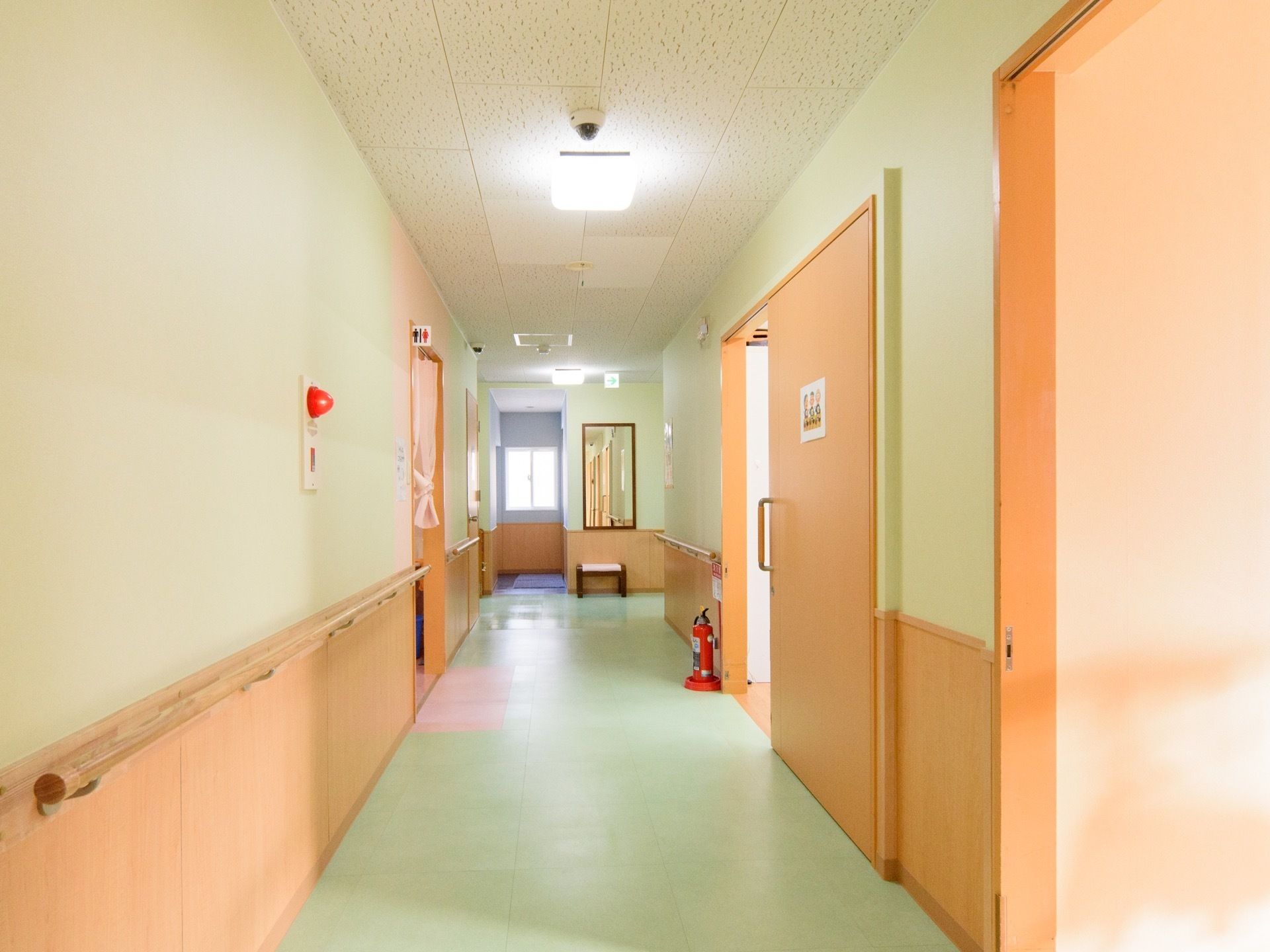 廊下の突き当りには、長方形の鏡が壁に貼ってあり、その下には腰かけ台が置いてある。廊下の床は、薄い緑色である。