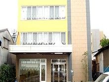 ３階建ての建物。敷地内には駐車スペースもあり、建物の玄関には雨除け用の屋根が付けられている。