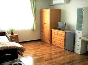 フローリングの居室。ベッドや収納家具が置かれ、窓が大きく明るい雰囲気。