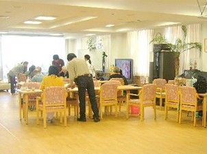 食堂では入居者とスタッフが集まり、穏やかな雰囲気。テレビも付き、テレビを見ている人もいる。