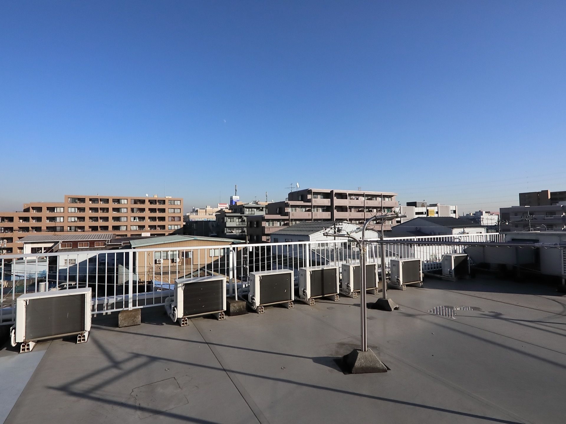 雨上がり後、雲ひとつない真っ青な空が広がった日の施設屋上からの景色である。物干し竿が設置されている。