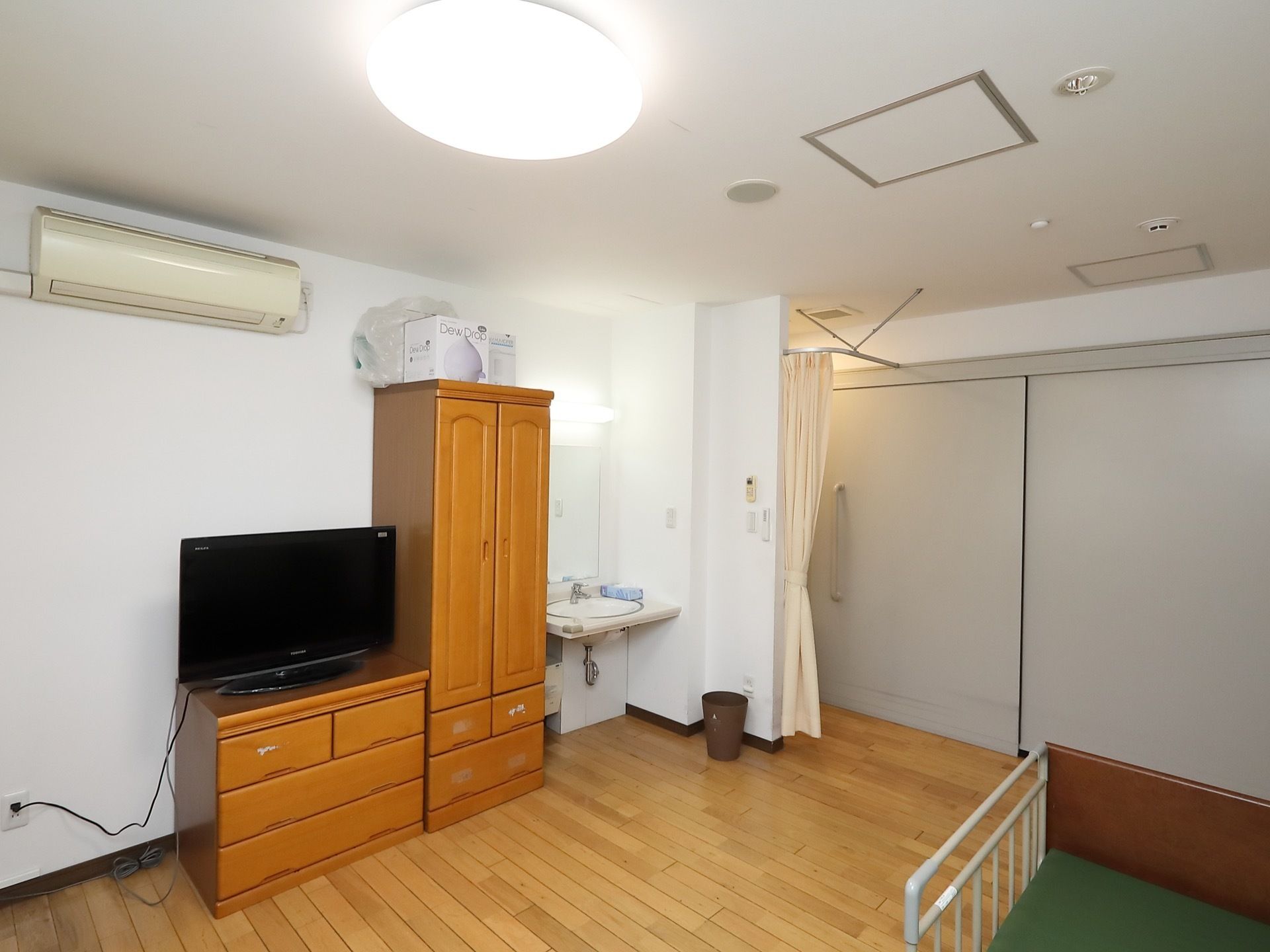 スライド式扉が設置されている居室には、介護用ベッドや収納クローゼットが配置され、チェストの上にはテレビが置かれている。