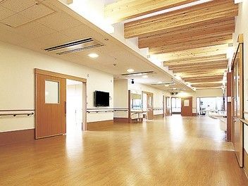 館内には木材をぜいたくに使い、家庭的な雰囲気。廊下は広く、壁掛けテレビや手すりの設置もある。
