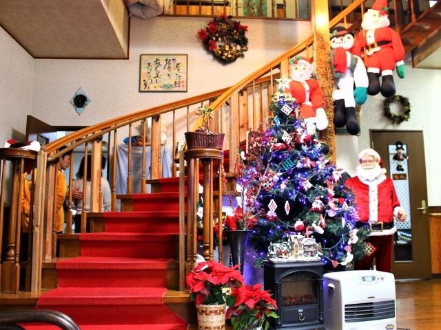 たくさんのオーナメントが飾られたクリスマスツリーが置かれ、その横の階段にはサンタやスノーマン、クリスマスリースが飾られている。