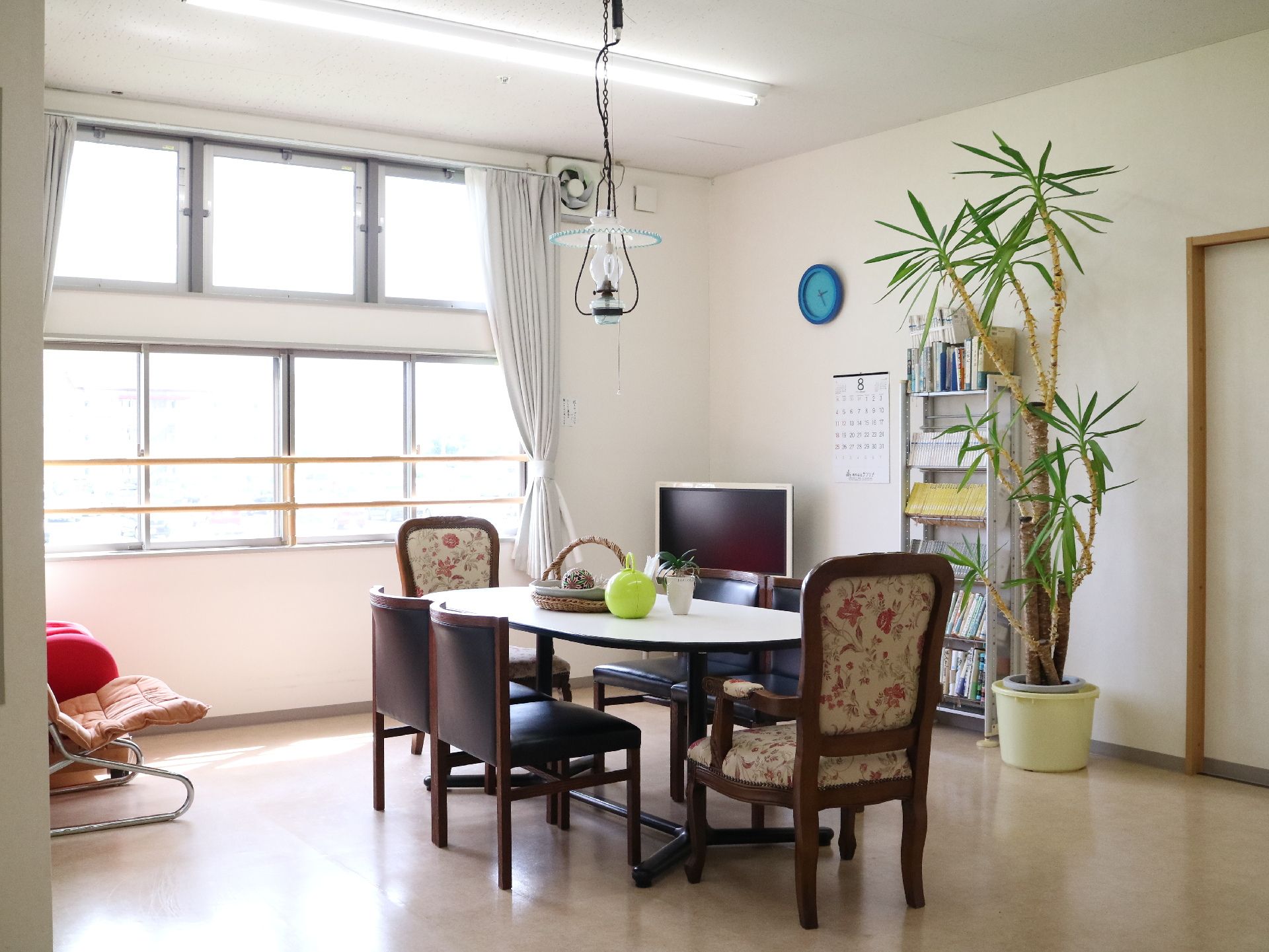 本棚、観葉植物が置かれていて、ペンダントライトがぶら下がっているリビング