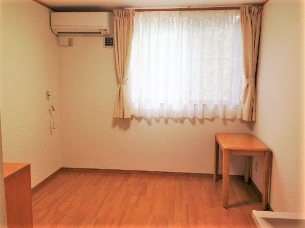 シンプルなフローリングの居室は窓が大きく、カーテンが設置されている。
