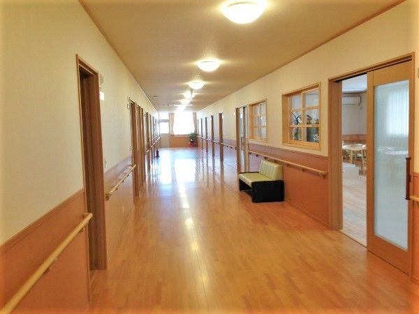 明るい雰囲気の廊下。奥には大きな窓があり、廊下にはベンチも置かれている。