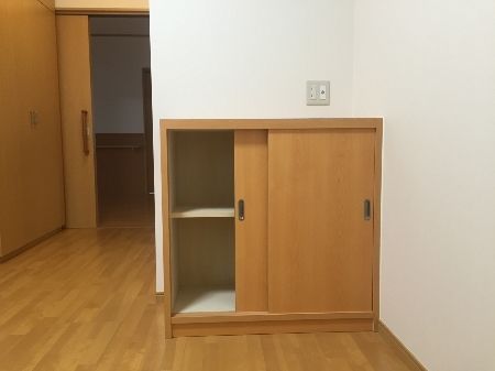 引き戸の小さな収納家具が付いたフローリングの居室。