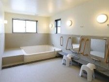ベンチが付いた白い浴槽は大きめで、洗い場が広く、シャワーが二つ、それぞれに洗面器や浴室用いすも付いている。