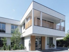 2階建ての建物の周りには緑が多く、白い建物がよく映える。玄関の上の階にはテラスもある。