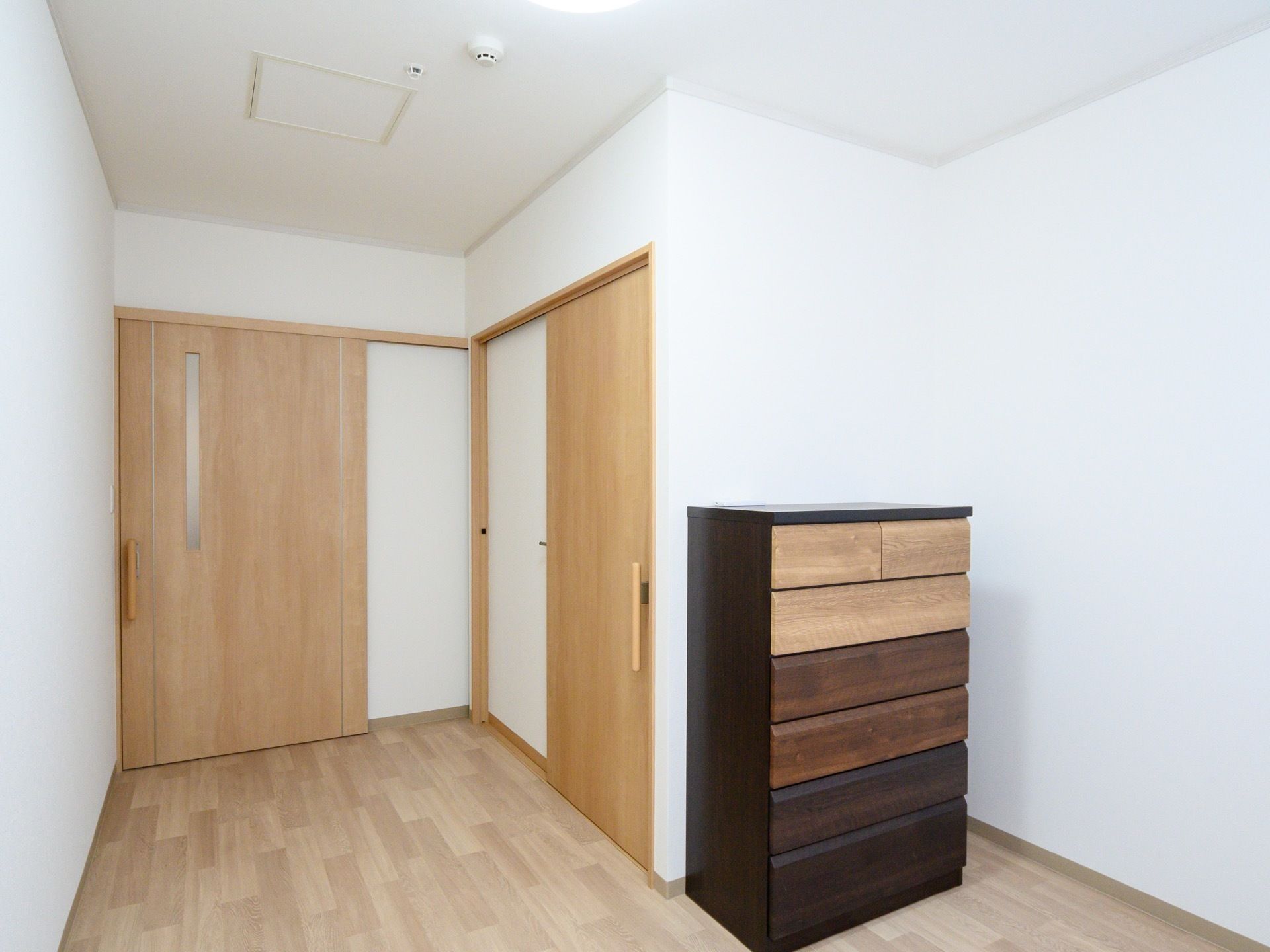 フローリングの床が使われた居室である。引き出しが六段ついている整理ダンスが据えられており、居室内にトイレが備わっている。