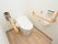 居室内にあるトイレである。フローリングの床に白い壁が使用されており、清潔感にあふれている。手すりが両側に備わっている。