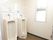 白い壁に囲まれた広いトイレがある。男性用の便器が２つ設置されている。窓には縦長の大きな窓が付いている。