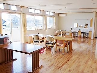 木製のダイニングテーブルが複数置かれ、ぬくもりが感じられる明るい食堂には洗面所もある。