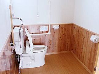 エル字型の手すりが設置されたトイレ。オレンジの呼び出しボタンや可動式の手すりもついている。