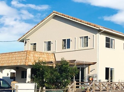 大きな窓があり明るい雰囲気の住まい。ウッドデッキが付いた洋風で2階建ての建物。