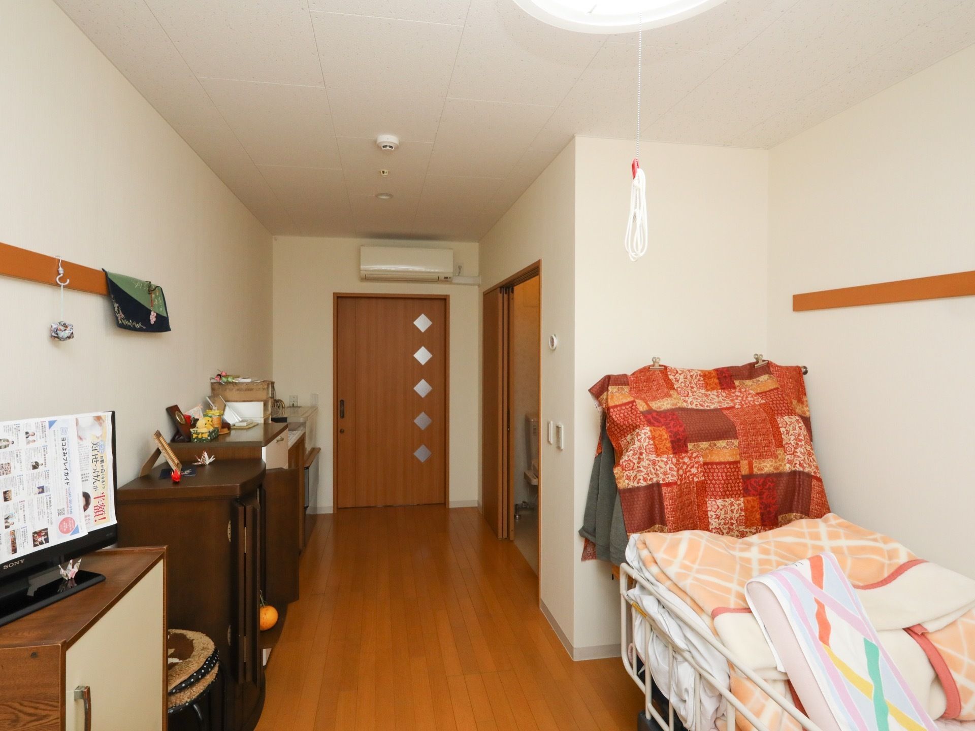 居室のドアの近くにエアコンが取り付けられている。壁沿いに収納家具がいくつか並んでいる。壁に物を掛けていただける。