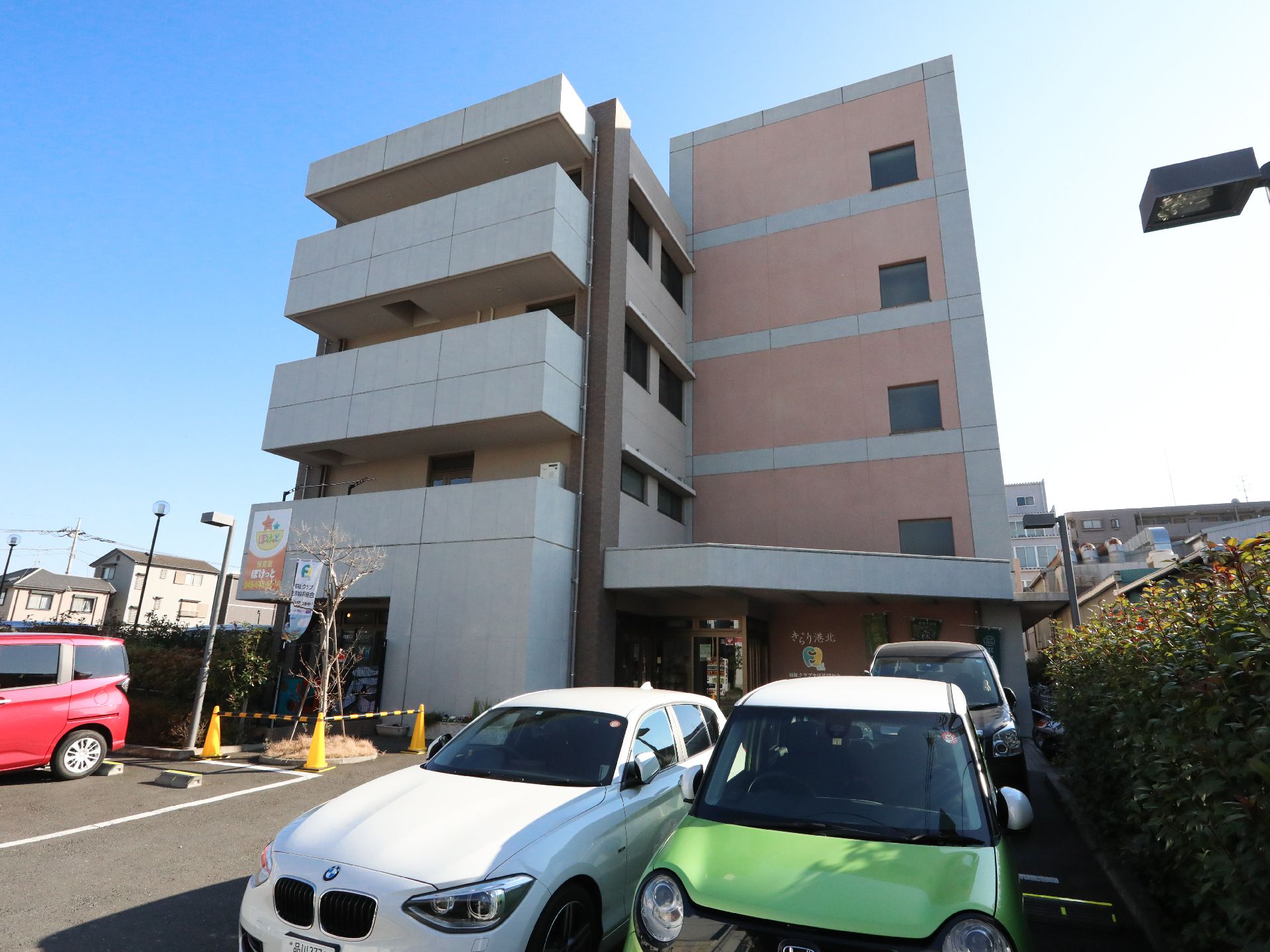 駐車場を所有しており、周囲を植栽で囲まれている外観の建物