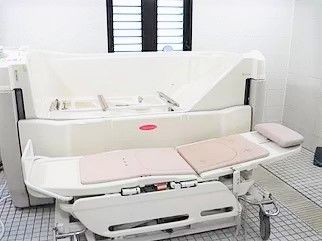 白とピンクの機械浴室。寝たまま入浴できる設備。