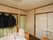 居室にトイレが備え付けられており、緑色のカーテンで仕切られている。室内には、ベッドや椅子が置かれている。