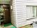 白を基調とした２階建ての住まい。建物前の電柱には照明が取り付けられており、敷地内には自転車が駐車されている。