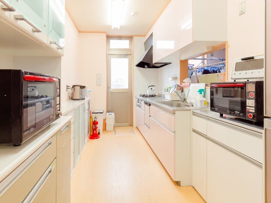 オーブンレンジなどの調理家電がそろったキッチン。大きな食器棚が付き、消火器も置かれている。