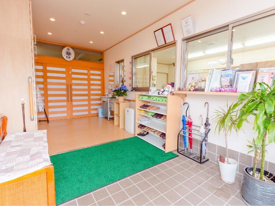 事務所がすぐそばにある玄関にはマットが敷かれ、靴箱や傘立て、観葉植物が置かれている。