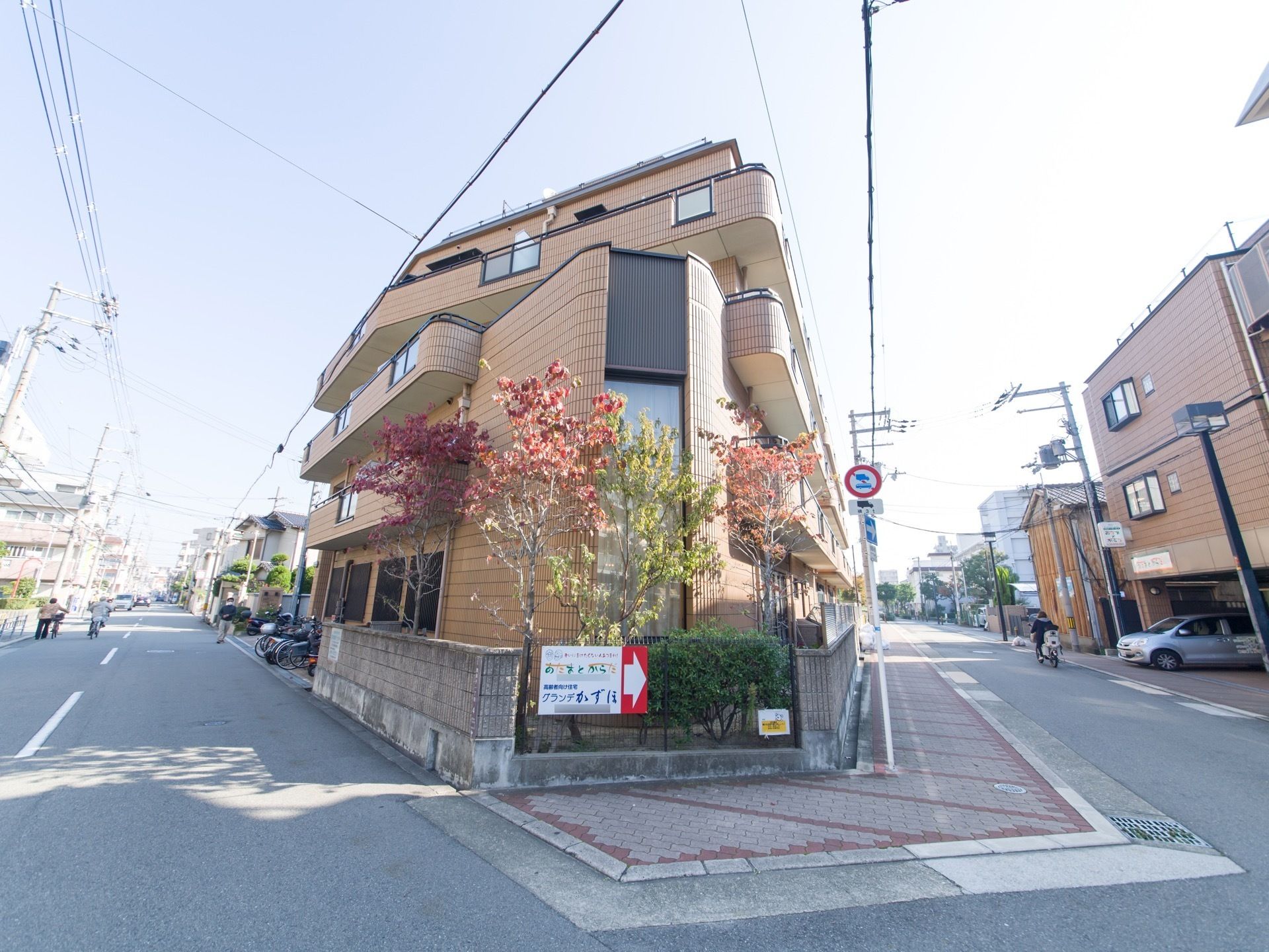 ブロック塀の施設外に、看板が設置されている。玄関への案内、問い合わせ先が記載されているのでいつでも問い合わせができる。