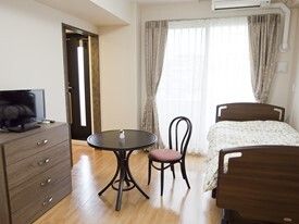 エアコンが付いたフローリングの部屋には大きな窓が付いている。寝具付きのベッドやテーブルセット、テレビなどもある。