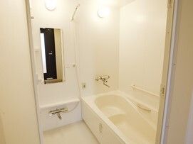 浴槽内にベンチが付いた一人用の浴室。鏡やシャワーが付き、手すりも複数設置されている。
