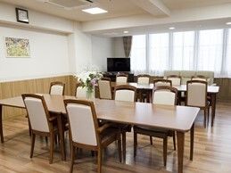 テレビが設置された食堂には長いダイニングテーブルが二つ置かれ、百合の花や絵画も飾られている。