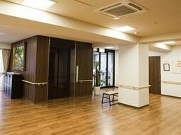 エレベーターの両サイドにも手すりが設置され、壁には絵画が飾られている。奥には自動ドアが設置されたエントランスがある。