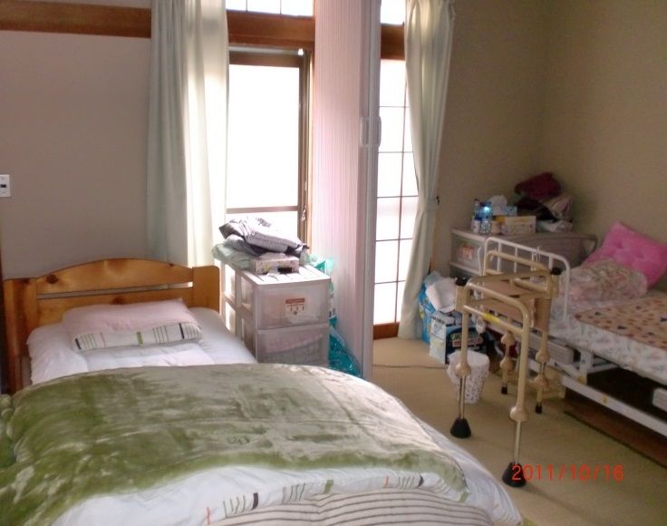 カーテンが付いた大きな窓がある部屋には２台のベッドが置かれ、中央にアコーディオンカーテンがある。