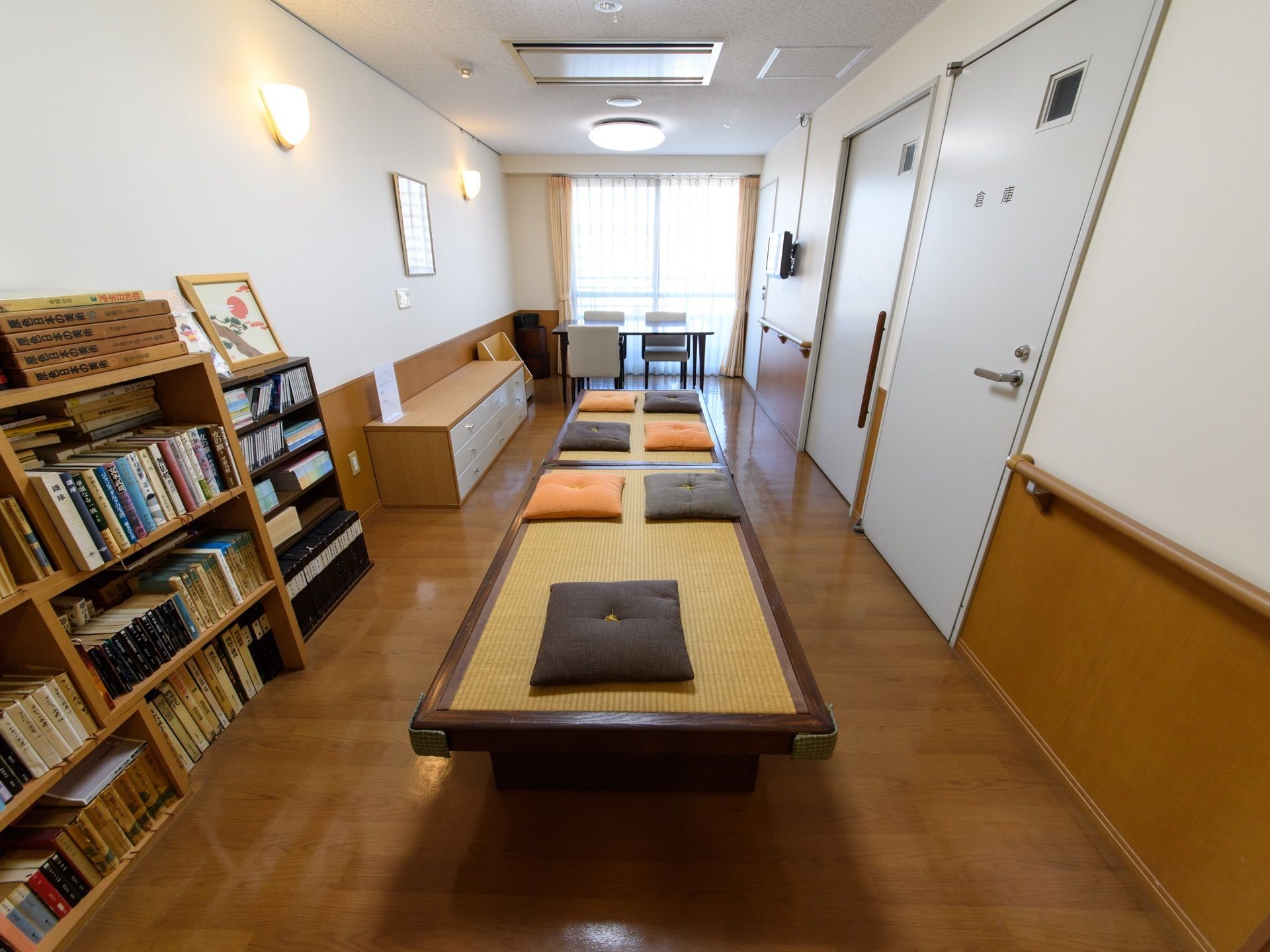 棚にはたくさんの本が置かれている。畳敷きのスペースがあり、座布団が何枚か置いてある。テーブルとイスもある。