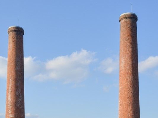 白い雲が浮かぶ青空に２本の大きな煙突が立っている様子。煙などはでていない。