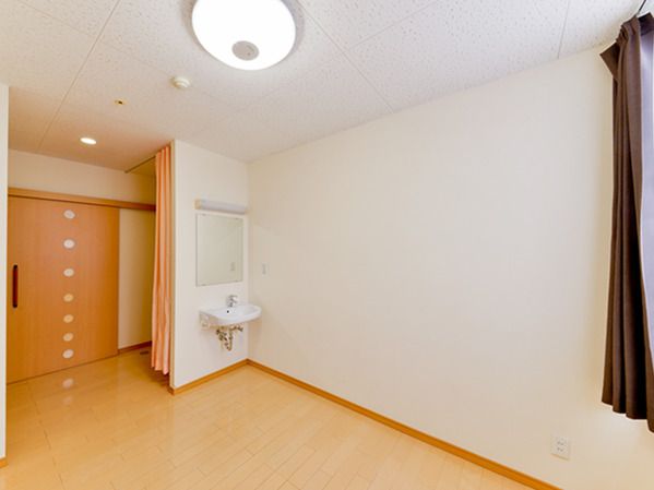 カーテンで開け閉めするタイプのトイレが付いたフローリングの部屋には車いす対応の洗面所もある。