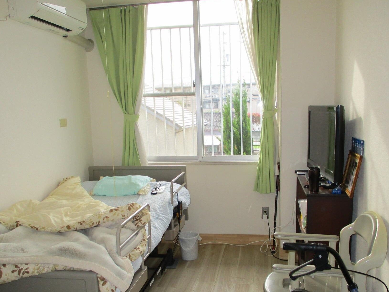 テレビや寝具付きのベッドが置かれ、エアコンが付いた一人用の部屋。大きな窓も付いている。