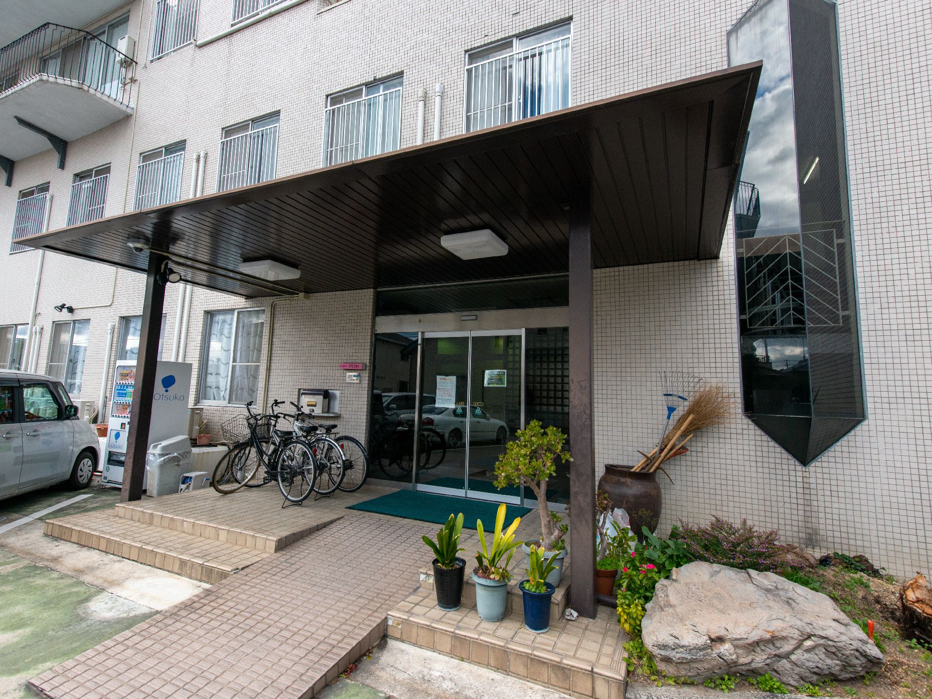 白を基調とした建物は３階建てで玄関先には自動販売機が付いていて、玄関にはスロープが付いている。