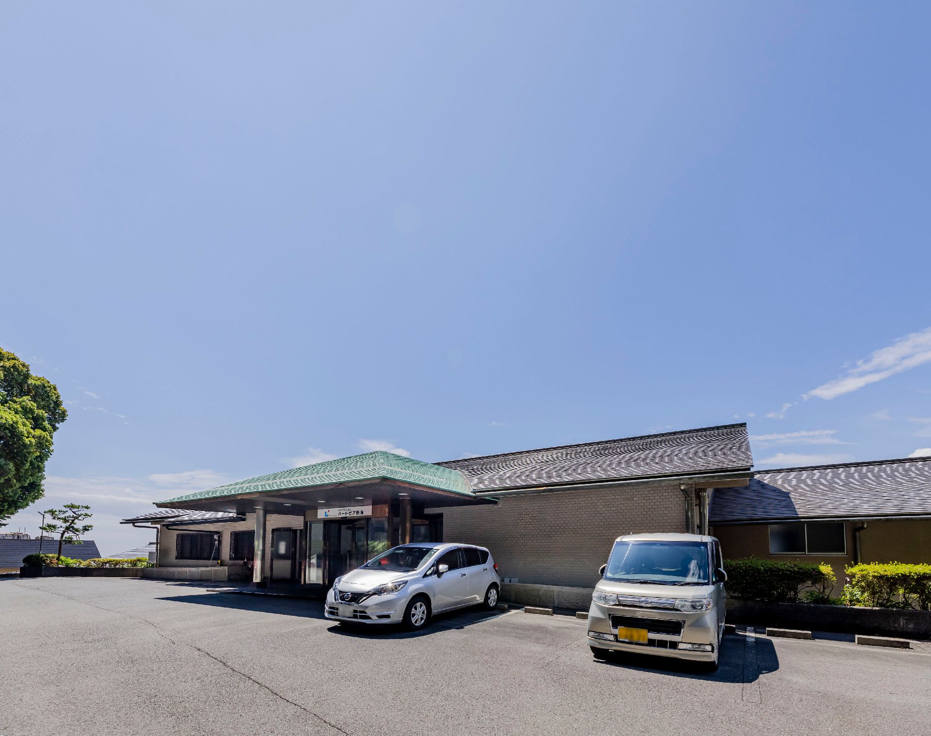 きれいな青空と2台の自動車が止まっている大きな建物