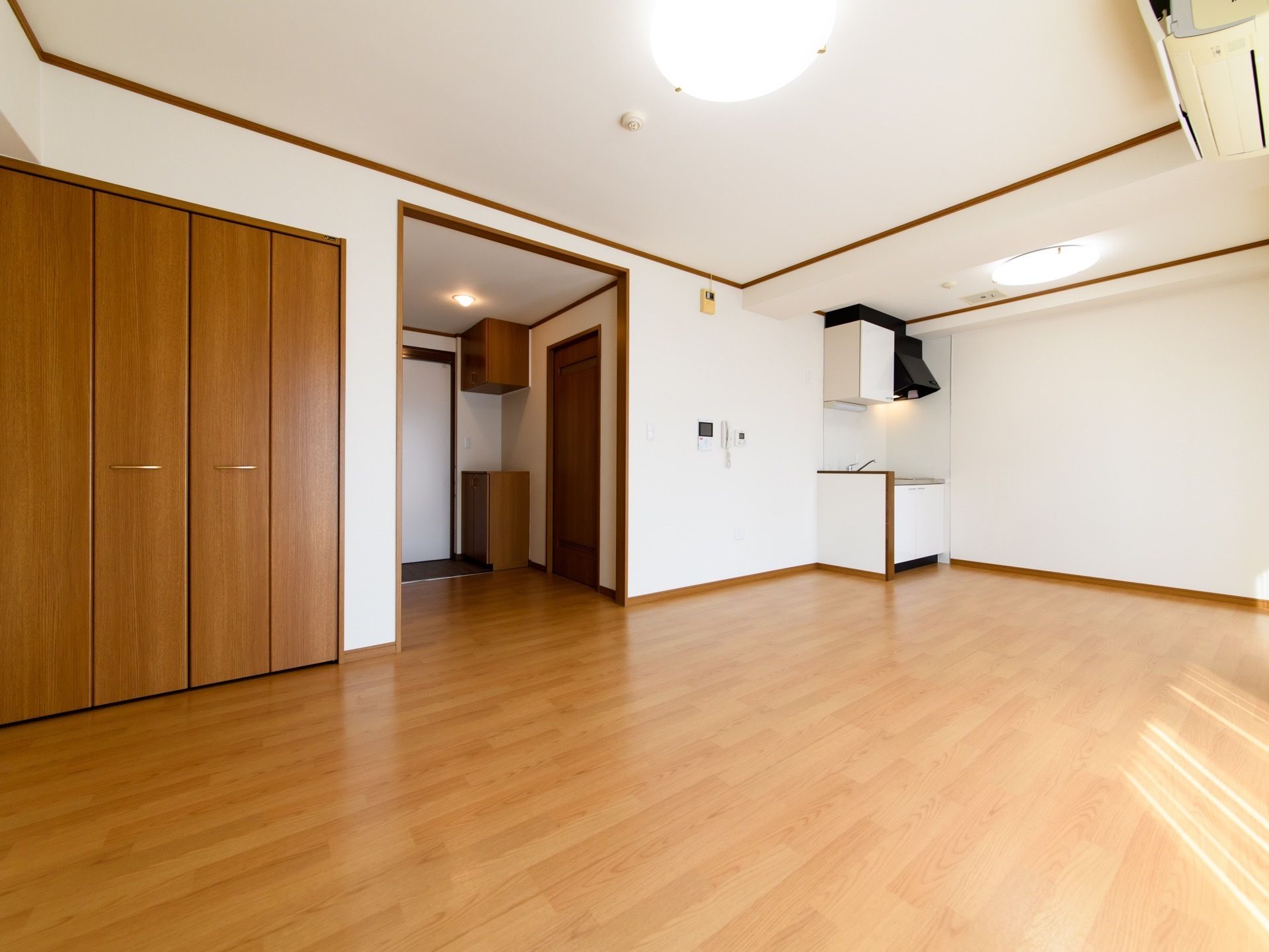 居室は広々としている。部屋の角にはコンパクトなキッチンが設置されている。横側にはインターフォンの画面がある。