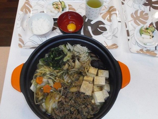 大きな鍋にすき焼き風の食べ物が作られている様子。豆腐や肉類が並ぶ鍋の写真