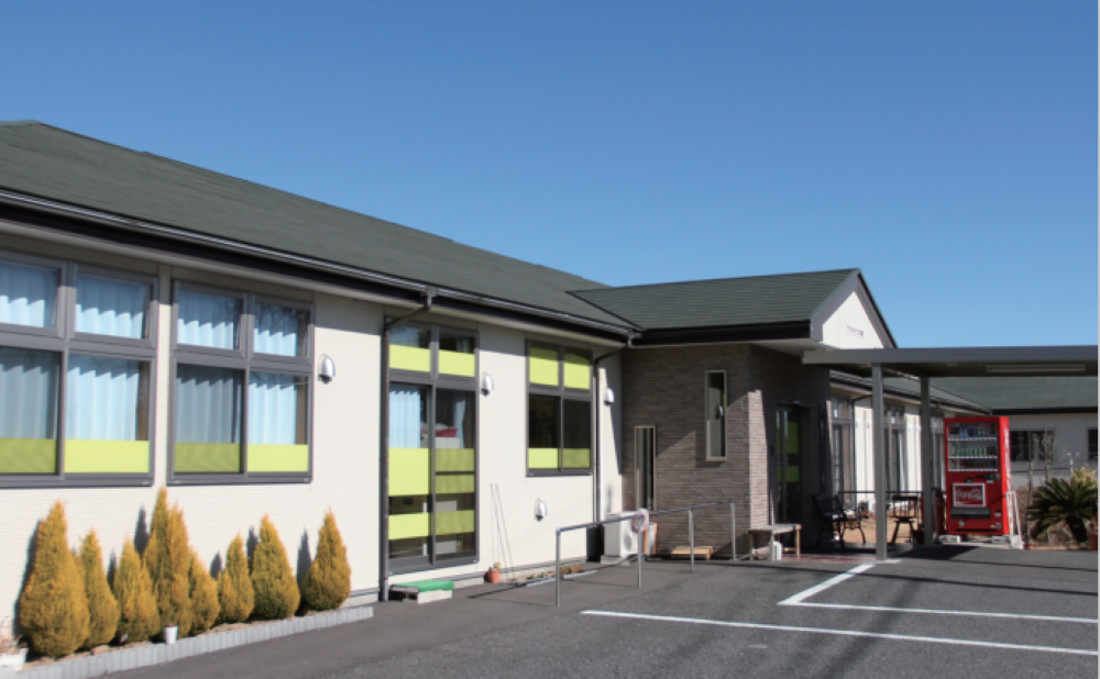 白とベージュの外壁で三角屋根の平屋建て老人ホーム