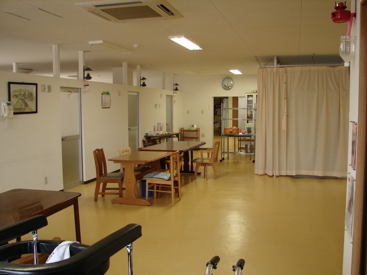 カメラに向かって笑顔を見せるスタッフと高齢者の女性。施設での何気ない一場面の様子