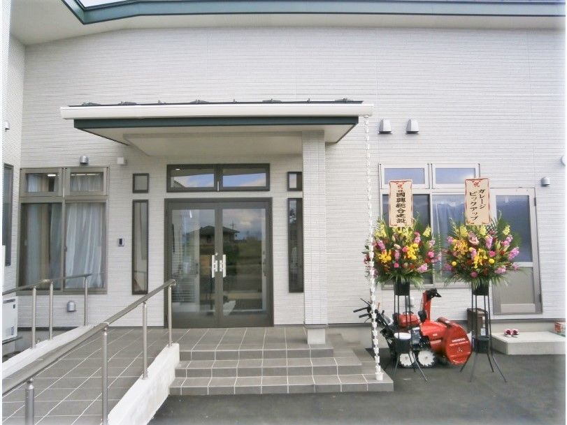 スロープと階段が設置された階段はガラスのドア。お祝いの花も玄関の横に飾られている。